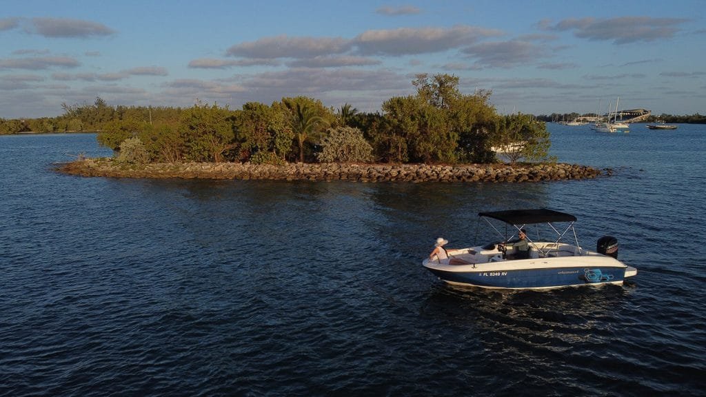 Bayliner E18 Blue rental boat beside mangroves, aerial view